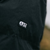 Close-up of a black waterproof jacket sleeve with water droplets on the surface, featuring a black rectangular 'PICTURE' brand patch on the upper arm.